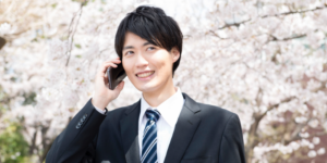桜の下で電話をする男性